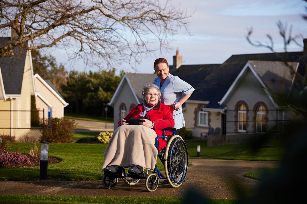 Health Assistant at Middletown Nursing Home in Gorey bringing a wheelchair-bound resident on a walk in the grounds