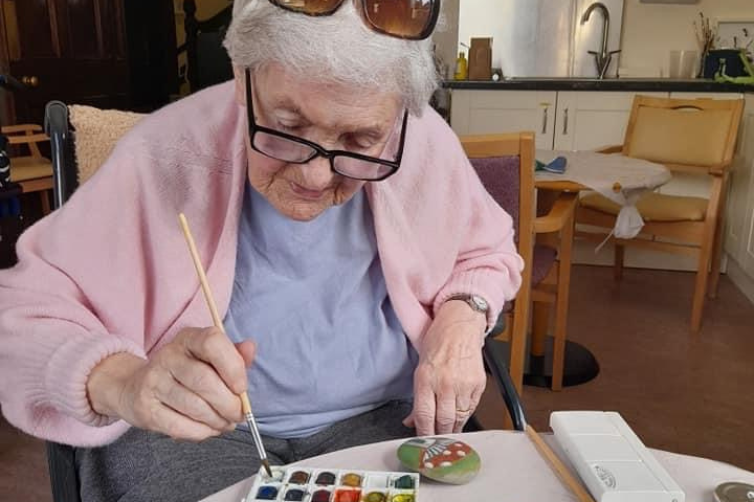 Photo of older lady painting stones in art class at Greystones Nursing Home
