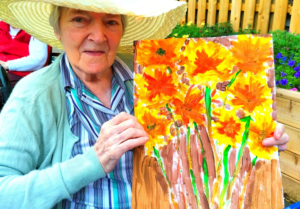 Lady resident with colourful painting at Mullinahinch House Nursing Home